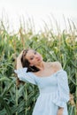 Young beautiful woman 26 years old in white simple dress in summer field. Green corn. Summer. Rustic style Royalty Free Stock Photo