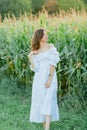 Young beautiful woman 26 years old in white simple dress in summer field. Green corn. Summer. Rustic style Royalty Free Stock Photo