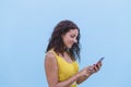 Young beautiful woman in yellow dress using mobile phone over a blue wall. Outdoors. Travel concept. City Royalty Free Stock Photo