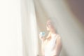 Young beautiful women drinking coffee in the mornng bedroom near window with white curtain overlay. Happy caucacian girl having a Royalty Free Stock Photo