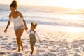 Happy black woman holding hands of daughter while walking on beach at sunset Royalty Free Stock Photo