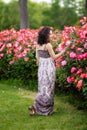 Young beautiful women walking in a rose garden, full body portrait, dark brown hair, brunette