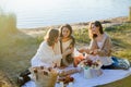 Young beautiful women of 25 years old on an autumn picnic near the lake. Glass of white wine, pastries. Happy models chatting Royalty Free Stock Photo