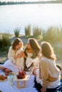 Young beautiful women of 25 years old on an autumn picnic near the lake. Glass of white wine, pastries. Happy models chatting