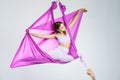 Young beautiful yogi woman doing aerial yoga practice in purple hammock