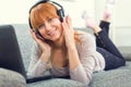 Young beautifull girl listening to music with headphones on her laptop at home