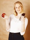 Young beauty blond teenage girl eating chocolate smiling, choice between sweet and apple Royalty Free Stock Photo