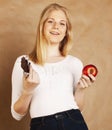 Young beauty blond teenage girl eating chocolate smiling, choice between sweet and apple Royalty Free Stock Photo