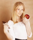 Young beauty blond teenage girl eating chocolate smiling, choice between sweet and apple Royalty Free Stock Photo