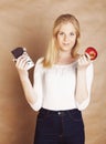 Young beauty blond teenage girl eating chocolate smiling, choice between sweet and apple Royalty Free Stock Photo