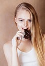 Young beauty blond teenage girl eating chocolate smiling close u Royalty Free Stock Photo