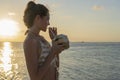 Young beauty girl drinking coconut at tropical beach near sea water at paradise island at sunset. Summer concept. Holiday travel Royalty Free Stock Photo