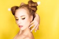 Young beauty girl with hair horns electic lamp hairstyle on a yellow background