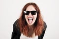 Young beauty hipster woman screaming and showing tongue, funny face with sunglasses Royalty Free Stock Photo