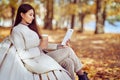 Young beauty woman sitting with a cup of coffee on a bench in the fall park Royalty Free Stock Photo