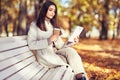 Young beauty woman sitting with a cup of coffee on a bench in the fall park Royalty Free Stock Photo