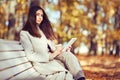 Young beauty woman sitting with a cup of coffee on a bench in the fall park Royalty Free Stock Photo