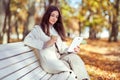 Young  beauty woman sitting with a cup of coffee on a bench in the fall park Royalty Free Stock Photo