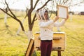 A young beekeeper girl is working with bees and beehives on the apiary, on spring day Royalty Free Stock Photo