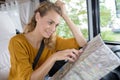 young bemused woman in campervan looking at map