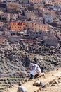 Young berber Muslim boy communicate on mobile sitting on mountain edge in Atlas village