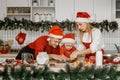 Young beutiful family wearing santa claus hats are in process of cutting cookies of gingerbread dough in Christmas decorated