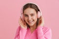 Young beutiful smiling girl enjoying music in pink headphones