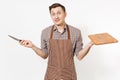 Young bewildered man chef or waiter in striped brown apron, shirt holding wooden cutting board, knife isolated on white Royalty Free Stock Photo