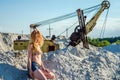 Young bewitching girl with long beautiful hair in denim shorts and a bikini bathing suit sitting on a mountain of sand in the Royalty Free Stock Photo