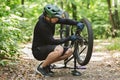 Young bicyclist fixing bike chain in forest