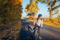 Young bicyclist riding on autumn field road at sunset. Happy woman traveler smiling Royalty Free Stock Photo