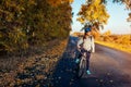 Young bicyclist riding in autumn field at sunset. Happy woman smiling Royalty Free Stock Photo