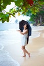 Young woman on beach holding umbrella checking for rain