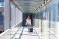 Young biracial businesswoman talking on phone while walking with luggage at airport corridor Royalty Free Stock Photo