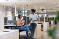 Young biracial colleagues discussing while eating lunch together in cubicle at modern workplace Royalty Free Stock Photo