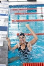 Young biracial female swimmer celebrating indoors in a pool, wearing goggles, copy space Royalty Free Stock Photo