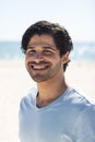 Young biracial man smiles brightly outdoors at the beach