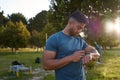 Young biracial man in t-shirt looking down at fitness tracker by trees in park Royalty Free Stock Photo