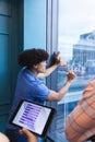 Young biracial man writing on graphs on window in a modern office Royalty Free Stock Photo