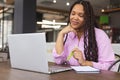 A young biracial woman with long braided hair is working on a laptop in a modern business office Royalty Free Stock Photo