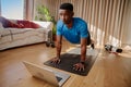 Young Black African American male working out at home holding a plank position about to do push ups on a yoga mat
