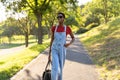 Young black African woman fashion model walking in a park with sunglasses and a handbag. Royalty Free Stock Photo