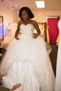 Young black african woman fitting dressed in luxury white gown standing in wedding shop dress salon