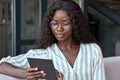 Young black African woman holding using digital tablet sitting on couch at home. Royalty Free Stock Photo