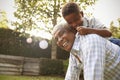 Young black boy climbing on his grandfatherÃ¯Â¿Â½s back in garden