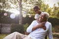 Young black boy embracing grandfather sitting in garden