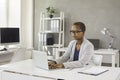 Young black business lady sitting at office table and working on laptop computer Royalty Free Stock Photo