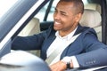 Young businessman driver sitting inside car driving looking at road cheerful side view in window close-up Royalty Free Stock Photo