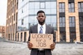 Young black businessman holding cardboard sign with the text LOOKING FOR A JOB, lost his job due to quarantine Royalty Free Stock Photo