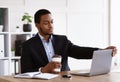 Young black businessman opening his notebook, drinking coffee, office interior